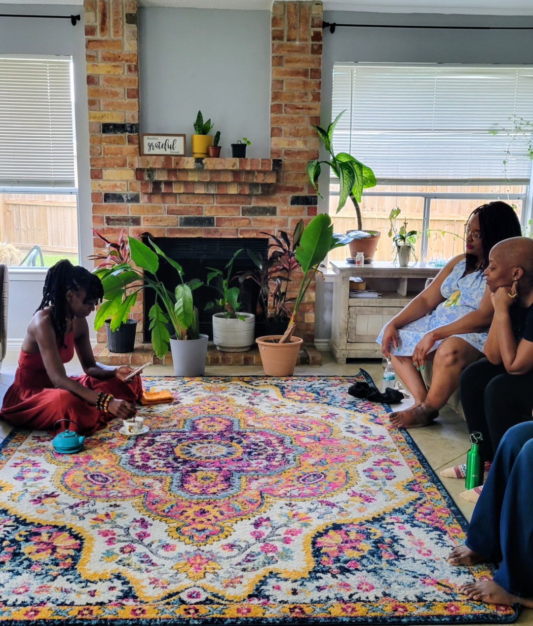 JC Jackson pouring tea for two women resting on a couch at the first We Rest as Reparations gathering