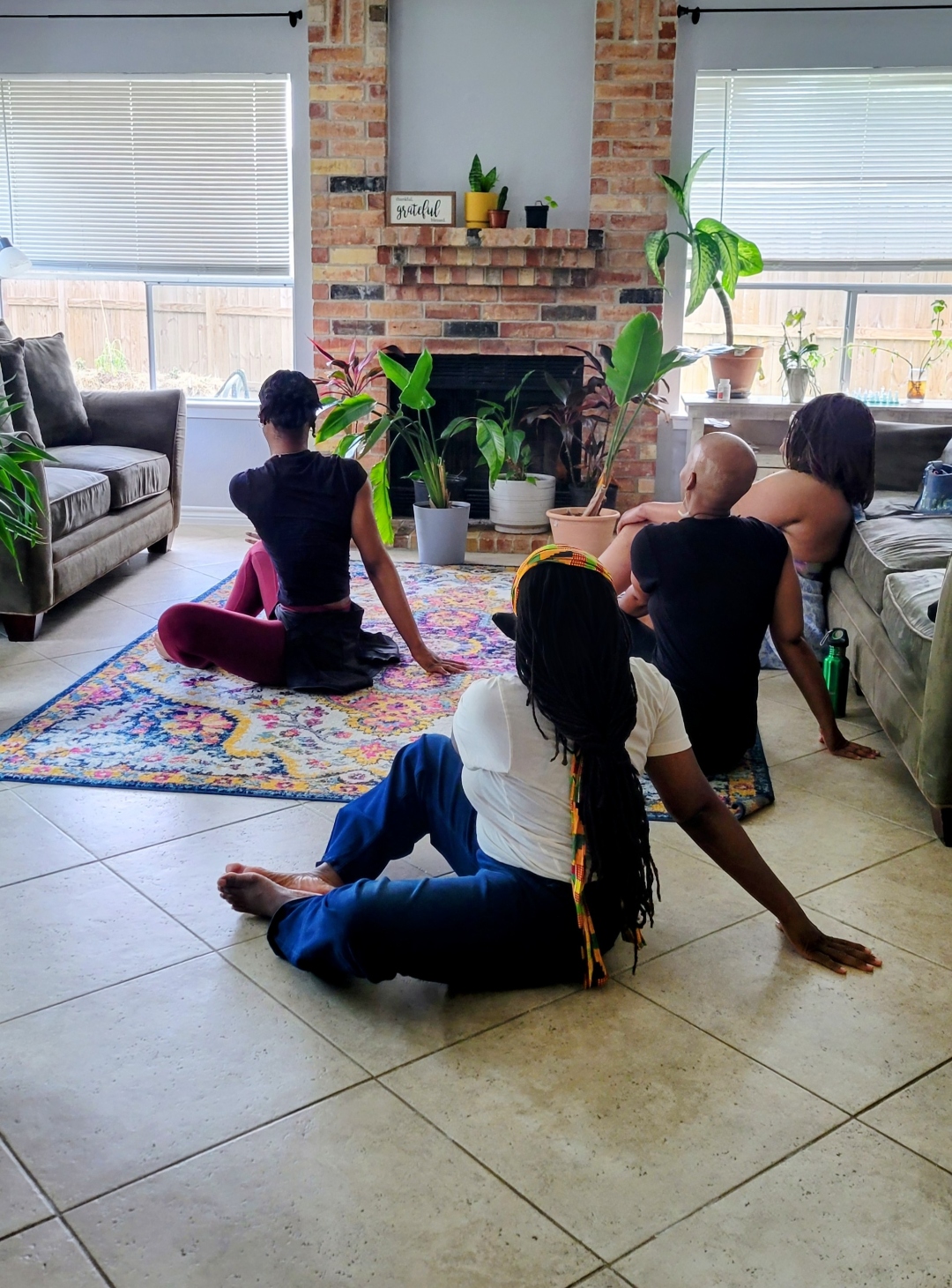 Black women stretching together in a sunlit living room at the first We Rest as Reparations gathering